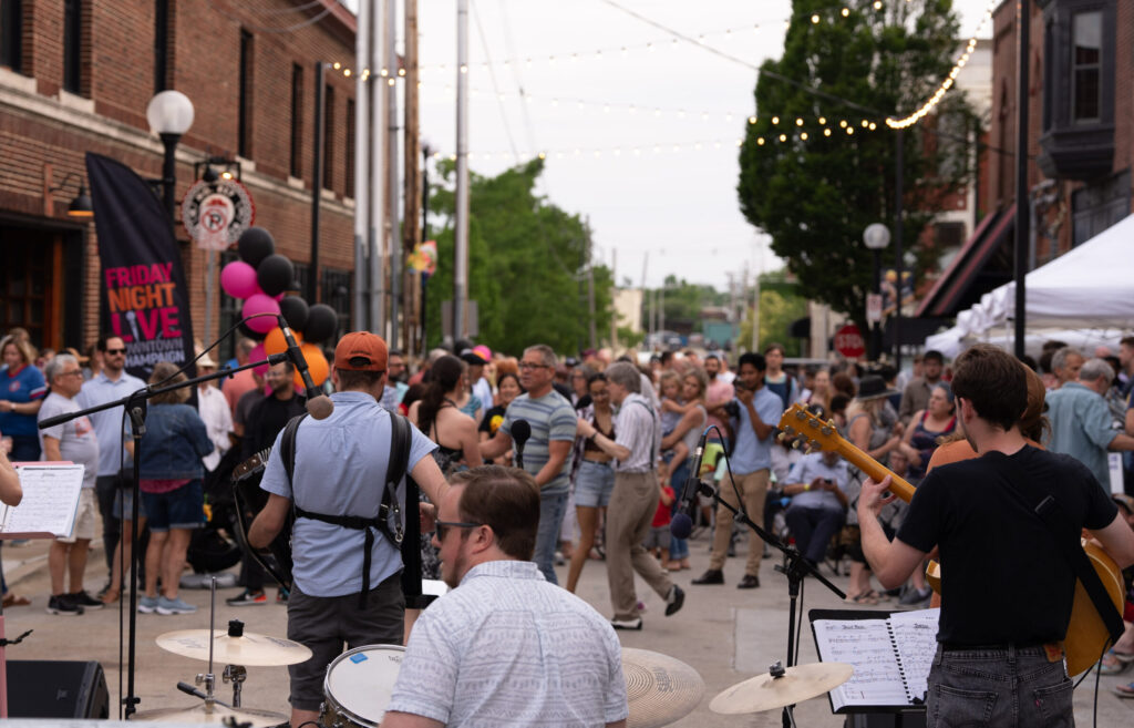 Image taken from behind a band performing to a large group of people at Friday Night Live in Downtown Champaign.